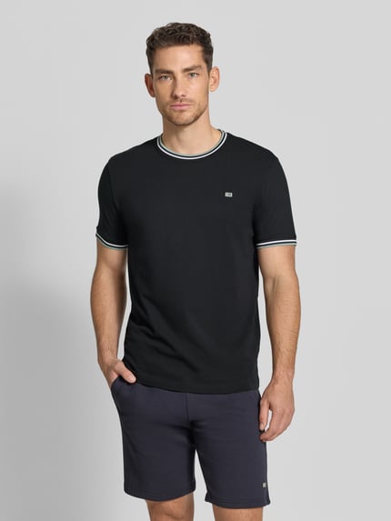 Männermodel trägt T-Shirt mit Kontraststreifen und Rundhalsausschnitt von Christian Berg Men, bawełna z elastanem, krój regular fit, czarny z białymi i zielonymi paskami przy kołnierzu i rękawach, długość tyłu w rozmiarze M: 71 cm, Ganzkörperansicht von vorne