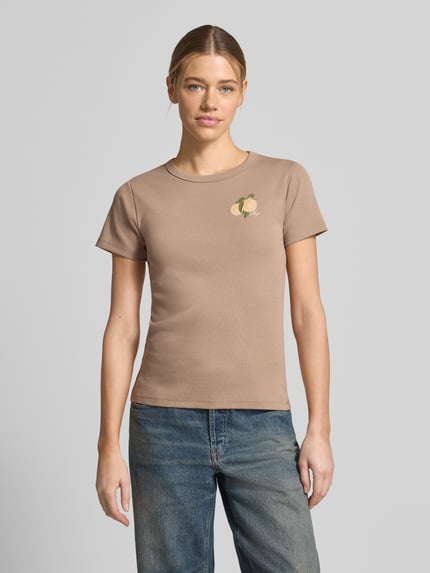 Modelka nosi Regular Fit T-Shirt aus Baumwoll-Mix Modell 'DELORIS_4' od HUGO, gładki jersey w kolorze beżowym z nadrukiem label oraz motywem graficznym, okrągły dekolt, krótki rękaw, widok całej sylwetki z przodu