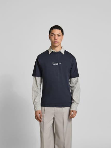 Męski model nosi Regular Fit T-Shirt mit Statement-Print von Closed, bawełna, krój regular fit, nadruk z napisem, okrągły dekolt, krótki rękaw, długość tyłu w rozmiarze M: 64 cm, widok z przodu całej sylwetki.