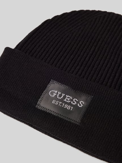 Produktfoto, schwarze Mütze aus Viskose-Mix in Strick-Optik von GUESS mit Logo-Patch und Strasssteinbesatz, Detailaufnahme.