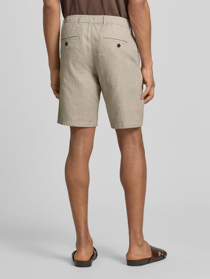 Männermodel trägt Slim Fit Bermudas aus Baumwoll-Leinen-Mix Modell 'BRODY' von SELECTED HOMME, efekt: jednolity kolor, aplikacja z marką, krój slim fit, szlufki na pasek, zapięcie na guzik i zamek błyskawiczny, tunel, wpuszczana kieszeń, kieszeń z tyłu, mieszanka bawełny i lnu, Ganzkörperansicht Rückansicht.