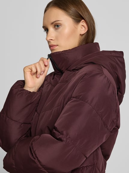 Frauenmodel trägt Regular Fit Steppjacke mit Kapuze Modell 'CLAIR' von ONLY in Bordeaux, glatte Textur, Nahaufnahme Oberkörper, Damen Steppjacke von ONLY