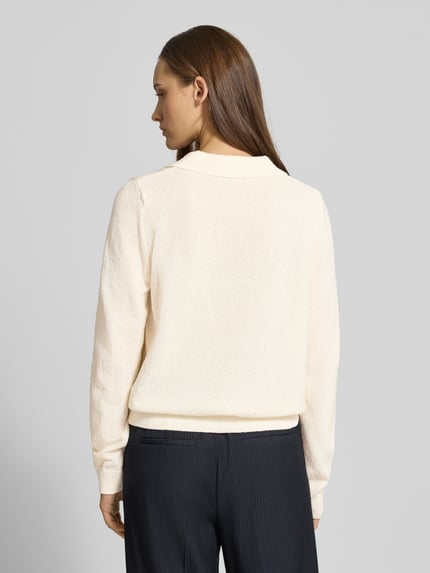 Vrouwenmodel draagt Langärmliger Polo-Strickpullover aus Bouclé-Garn van Review in crème, bouclé-look, los model, elastische boorden, ruglengte maat S 55 cm, mouwlengte maat S 65 cm, geheellichaamsbeeld achteraanzicht.