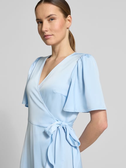 Frauenmodel trägt Cocktailkleid mit Volantsaum Modell 'THEA' von YAS aus hellblauem Satin, taillierter Schnitt, Wickel-Optik, V-Ausschnitt, Schmetterlingsärmel, Nahaufnahme Oberkörper. Rückenlänge bei Größe 36: 120 cm, Brustweite: 39 cm, Ärmellänge: 27 cm.