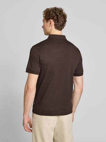 Męski model nosi Slim Fit Poloshirt mit Reißverschluss Modell 'Franciscojose' od JOOP! Collection, czysta bawełna, krój slim fit, brązowy kolor, teksturowany materiał, widok całej sylwetki od tyłu.
