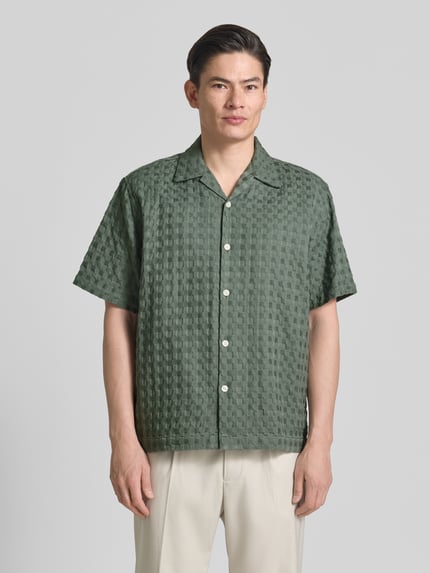 Męski model nosi Relaxed Fit Freizeithemd aus reiner Baumwolle Modell 'MONTY' von SELECTED HOMME, efekt: jednolity kolor, krój relaxed fit, kołnierzyk koszulowy, na całej długości listwa guzikowa, pas na plecach, zapięcie: listwa guzikowa jednorzędowa, rękaw: krótki rękaw, wykończenie materiału: żakard, materiał: bawełna. Ganzkörperansicht von vorne.