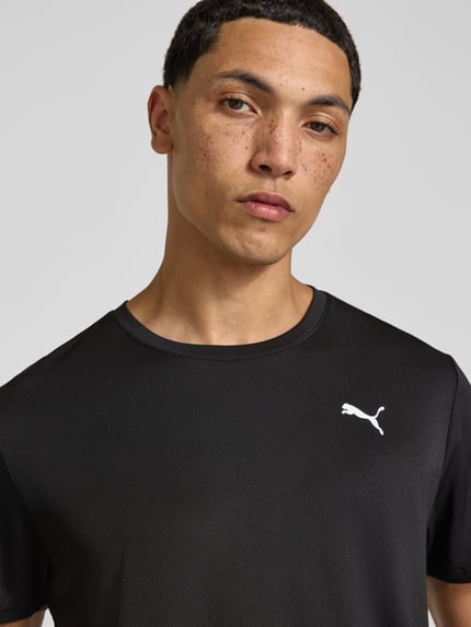 Männermodel trägt zwart Regular Fit Sport-T-Shirt mit Logo-Print Modell 'TAD Essential' van PUMA Performance, Nahaufnahme Oberkörper.