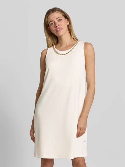 Vrouwenmodel draagt Relaxed Fit jurk met viscose van ROBE LÉGÈRE in crème, mouwloos design, siergarnering, knielengte, ronde hals. Nahaufnahme Oberkörper. Ruglengte maat 36: 94 cm, borstwijdte maat 36: 47 cm.