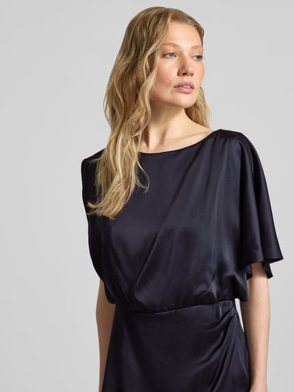 Vrouwenmodel draagt glanzend one-shoulder midi-jurk van comma, materiaalmix met viscose, recht model, ronde hals, one-shoulder look, ruglengte maat 36: 118 cm, borstwijdte maat 36: 35 cm, Nahaufnahme Oberkörper.