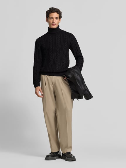 Męski model nosi Slim Fit Strickpullover mit Baumwoll-Anteil Modell 'Callum' von JACK & JONES Premium, czarny sweter z mieszanki materiałów z bawełną, wzór warkoczowy, długie rękawy, ściągaczowy golf i wykończenia, krój slim fit, całkowita długość z przodu, oni, Ganzkörperansicht von vorne.