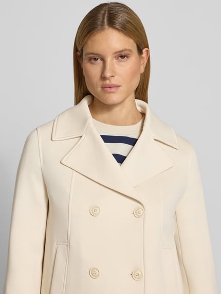 Vrouwenmodel draagt Regular Fit sweatjack met viscose van s.Oliver RED LABEL in crème, reverskraag, dubbele knoopsluiting, steekzakken, sweatmateriaal. Nahaufnahme bovenlichaam.