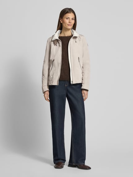 Frauenmodel trägt Jacke mit Kapuze und Reißverschlusstaschen von Gil Bret in Beige, kombiniert mit dunkler Hose, Ganzkörperansicht von vorne, Regular Fit, Kapuze mit Tunnelzug, Stehkragen, Reißverschluss und Reißverschlusstaschen, Rückenlänge 59 cm, Schulterbreite 40 cm, Brustweite 51 cm, Ärmellänge 63 cm.
