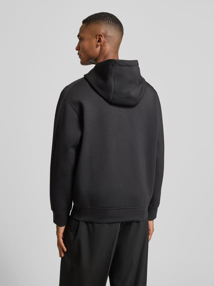 Mężczyznamodel nosi Bluza rozpinana z zamkiem błyskawicznym dwustronnym od Armani, mieszanka materiałów z modalem, krój regular fit, kaptur, naszywka z logo, wpuszczane kieszenie, długość tyłu 68 cm, długość rękawów 61 cm, widok całej sylwetki z tyłu.