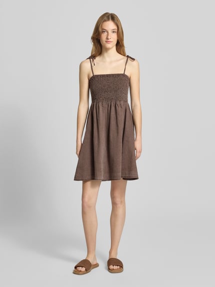Frauenmodel trägt Minikleid mit Smok-Detail Modell 'Oregon' von Noisy May aus reiner Baumwolle, taillierte Passform, braune Farbe, Ganzkörperansicht von vorne.