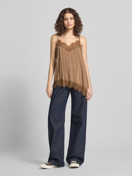 Frauenmodel trägt Relaxed Fit Top aus Viskose-Mix Modell 'Tami' von OH APRIL in Braun mit Spitzenbesatz und Spaghetti-Trägern, Ganzkörperansicht von vorne.