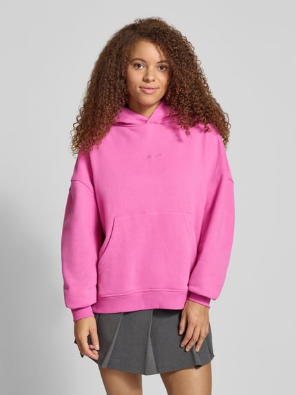 Frauenmodel trägt Hoodie mit rückseitigem Motiv-Print Modell 'Nostalgia Heart' von OH APRIL in Pink, Baumwoll-Mix, oversized, Känguru-Tasche, Nahaufnahme Oberkörper.