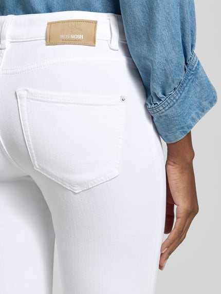 Männermodel trägt Jeans aus Viskose-Mix Modell 'Ashley' von MOS MOSH, krój slim fit, wpuszczane kieszenie, mieszanka wiskozy i lyocellu, szerokość w rozmiarze 27: 48 cm, długość wewnętrzna nogawki 73 cm, jasna biel, gładka faktura, detal tyłu, Nahaufnahme biodra