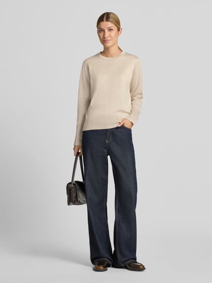 Frauenmodel trägt Strickpullover aus Viskose-Mix Modell 'KATIE' von FREE/QUENT in Beige mit geradem Schnitt, Jeans und Tasche, Ganzkörperansicht von vorne.