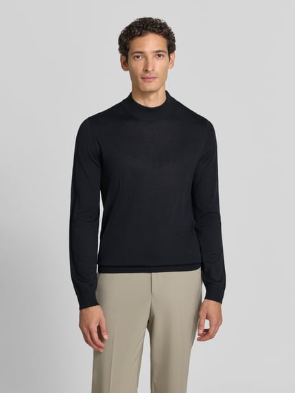 Männermodel trägt Regular Fit Turtleneck aus Woll-Mix von Christian Berg Men in Schwarz, glatte Textur, gerippte Abschlüsse, Ganzkörperansicht von vorne. Rückenlänge bei Größe M: 69 cm, Ärmellänge bei Größe M: 51 cm.