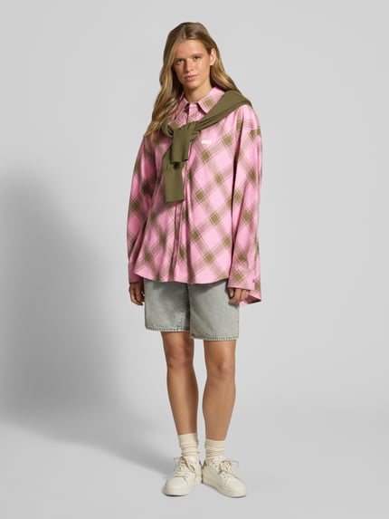 Kobiece model prezentuje bluzka z bawełny o kroju relaxed fit Relaxed Fit Bluse mit Label-Detail Modell 'Vivian' od OH APRIL, wzór na całej powierzchni, kołnierzyk koszulowy, detal z logo, długość tyłu w rozmiarze S: 80 cm, długość rękawów w rozmiarze S: 58 cm, jasnoróżowy z oliwkowymi i białymi akcentami, luźny fason, gładka tekstura, widok całej sylwetki z przodu.