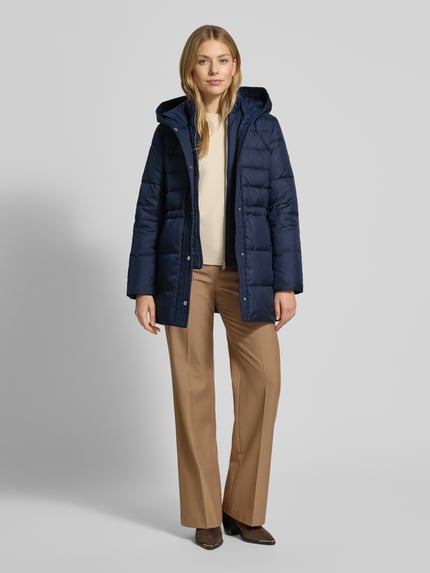 Frauenmodel trägt Daunenmantel mit Kapuze von Lauren Ralph Lauren in Dunkelblau, taillierter Schnitt, Stehkragen, Eingrifftaschen, Ganzkörperansicht von vorne.