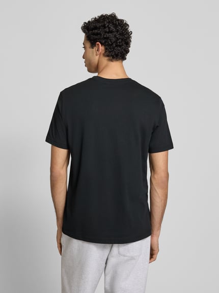 Männermodel trägt zwart T-shirt met labelstitchings en ronde hals, puur katoen, regular fit, ruglengte maat M 69 cm, CHAMPION. Ganzkörperansicht Rückansicht.