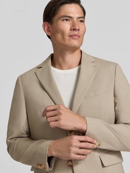 Männermodel trägt Regular Fit Sakko mit Viskose-Mix Modell 'Charles' von Matinique in Beige, glatte Textur, Nahaufnahme Oberkörper.
