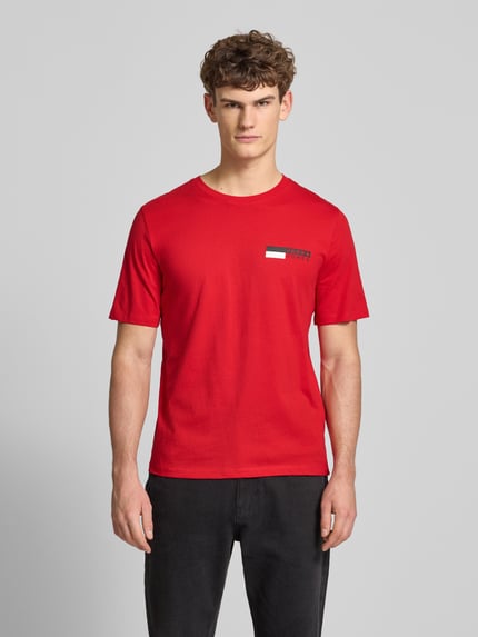 Męski model nosi czerwony T-Shirt mit Label-Print Modell 'CORP' od JACK & JONES, bawełna, prosty krój, widok całej sylwetki z przodu.