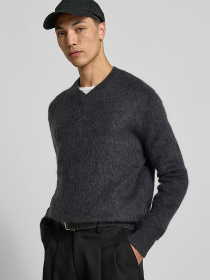 Männermodel trägt Regular Fit Pullover mit V-Ausschnitt von ANNARR, Strick-Optik, dunkles Grau, gerippte Abschlüsse, Nahaufnahme Oberkörper.