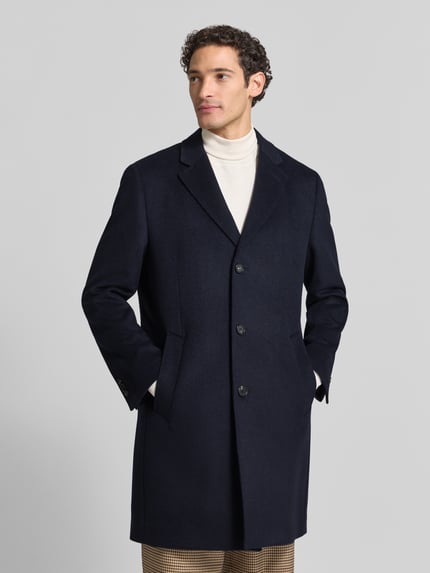 Männermodel trägt Mantel mit Reverskragen und Eingrifftaschen von bugatti, dunkelblau, Regular Fit, Knopfleiste, Ganzkörperansicht von vorne. Rückenlänge 99 cm, Schulterbreite 45 cm, Brustweite 57 cm, Ärmellänge 66 cm.