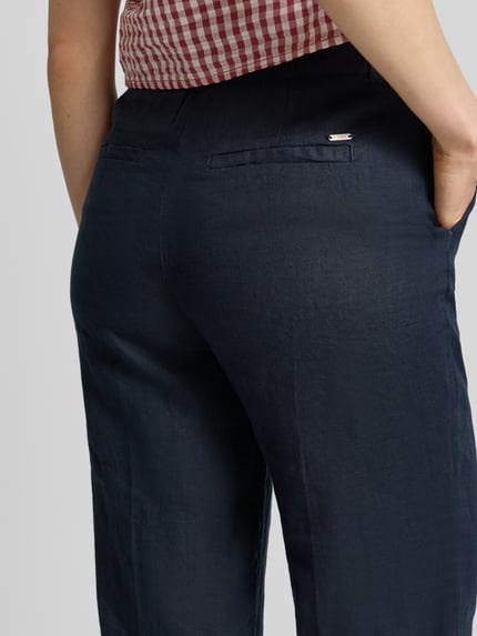 Frauenmodel trägt Leinenhose in verkürzter Passform von Christian Berg Woman, reines Leinen, Eingrifftaschen, Paspeltaschen am Gesäß, Nahaufnahme Rückansicht.