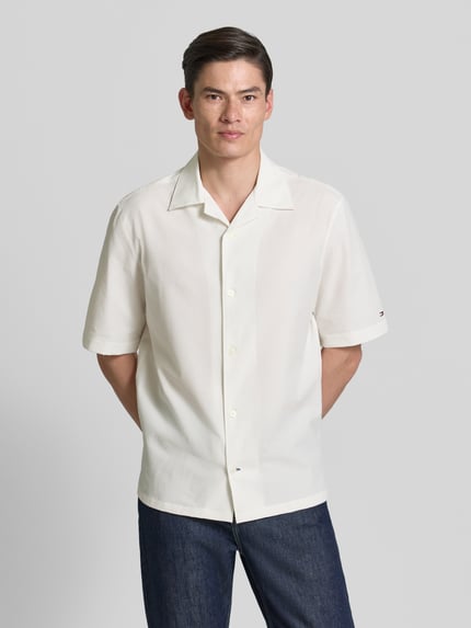 Męski model nosi Relaxed Fit Freizeithemd aus Seersucker-Material od Tommy Hilfiger, kremowy, allover-wzór, luźny krój, krótkie rękawy, seersucker, widok całej sylwetki z przodu.
