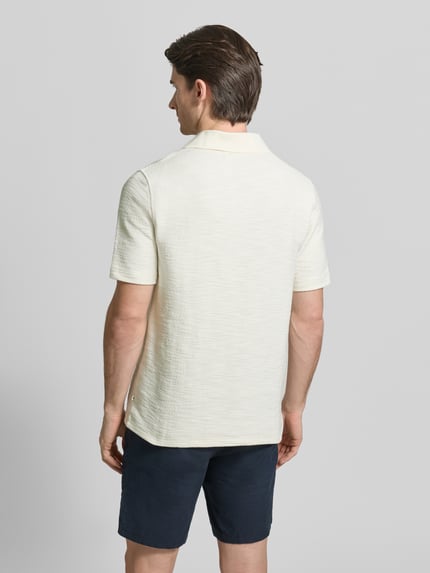 Männermodel trägt Regular Fit Poloshirt mit Polokragen Modell 'SAMAC' von Samsøe Samsøe in Creme, Kurzarm, strukturierte Oberfläche, Ganzkörperansicht Rückansicht.