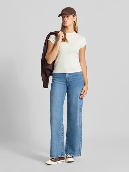 Frauenmodel trägt T-Shirt mit Rundhalsausschnitt Modell 'EVERYDAY' von Topshop in Weiß aus reiner Baumwolle, kombiniert mit blauer Jeans, gerader Schnitt, dezente Farben, Ganzkörperansicht von vorne. Rückenlänge bei Größe S beträgt 58 cm.