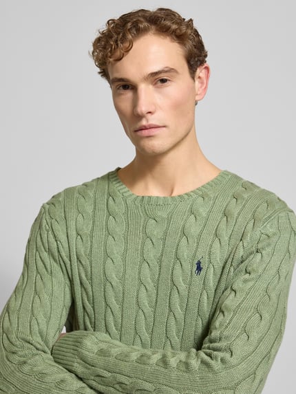 Männermodel trägt Strickpullover mit Label-Stitching von Polo Ralph Lauren aus reiner Baumwolle in Grün, Nahaufnahme Oberkörper.