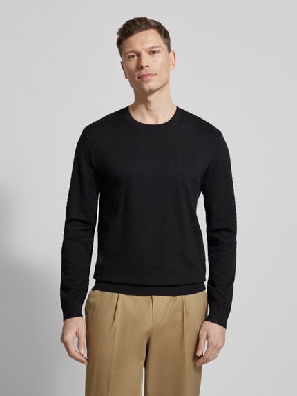 Männermodel trägt schwarzen Strickpullover aus Viskose-Mix von ARMANI EXCHANGE, Rundhalsausschnitt, elastische Abschlüsse, Ganzkörperansicht von vorne.