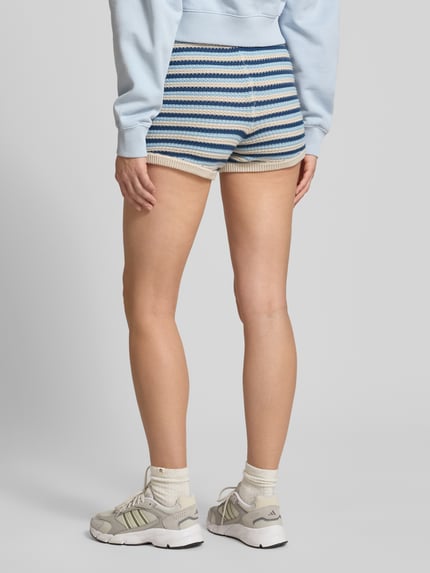 Frauenmodel trägt Shorts in Strick-Optik von Pegador in Blau-Beige mit Label-Patch, Reine Baumwolle, Körpernahe Passform, Ganzkörperansicht Rückansicht.
