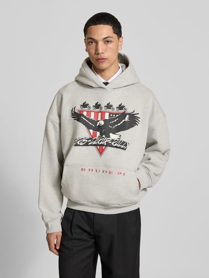 Männermodel trägt Oversized Hoodie aus katoenmix van RHUDE met labelprint en kangoeroezak, ribboorden, ruglengte maat M 64 cm, Ganzkörperansicht von vorne