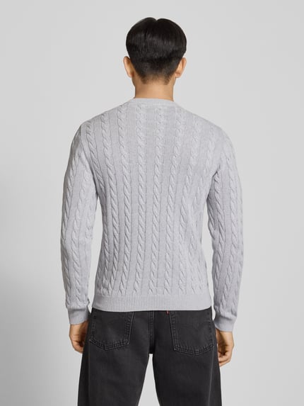Mężczyzna nosi Strickpullover mit Zopfmuster und Logo-Stitching od REVIEW, bawełniany, krój modern fit, jasnoszary, fason z okrągłym dekoltem, widoczne sploty, prążkowane ściągacze, całkowity widok z tyłu.