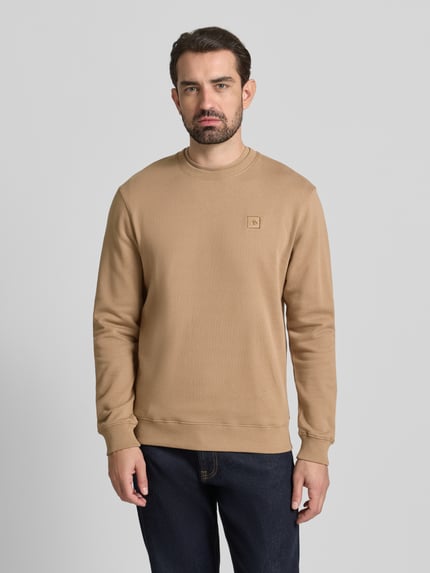 Männermodel trägt T-Shirt mit Label-Stitching van Scotch & Soda in beige, pure katoen, regular fit, ribkraag, Ganzkörperansicht von vorne.