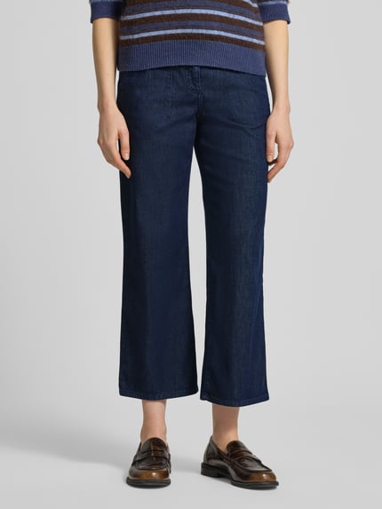 Frauenmodel trägt Wide Leg Jeans in verkürzter Passform Modell 'Maine' von Brax, dunkelblauer Baumwoll-Mix, Nahaufnahme Oberkörper bis Knöchel.