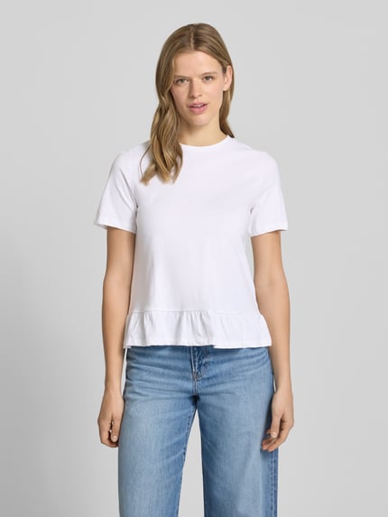 Frauenmodel trägt Regular Fit T-Shirt aus reiner Baumwolle Modell 'DISSO' von Pieces, unifarben weiß mit Rüschenbesatz, Ganzkörperansicht von vorne.