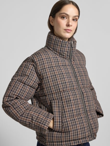 Frauenmodel trägt Steppjacke mit Stehkragen Modell 'LAURI' von MANGO mit Reißverschluss, Karomuster, Allover-Look, Nahaufnahme Oberkörper.