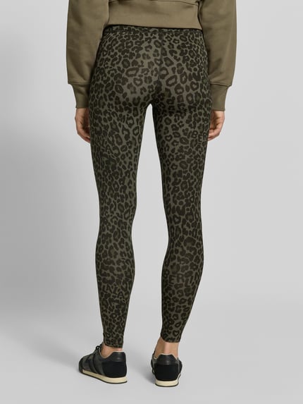 Frauenmodel trägt Leggings aus Viskose-Mix von Lala Berlin mit Leopardenmuster in Olive, eng anliegend, High Waist, Knöchellänge, Ganzkörperansicht Rückansicht.
