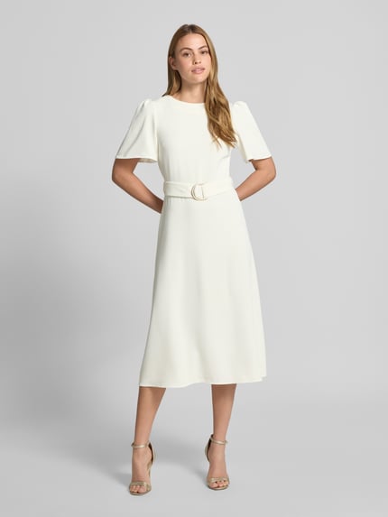 Frauenmodel trägt Cocktailkleid mit Gürtel und Rundhalsausschnitt von Rinascimento, weiß, Material-Mix mit Stretch-Anteil, taillierter Schnitt, Midikleid, rückseitiger Reißverschluss, Rückenlänge 36 cm, Brustweite 40 cm, Ärmellänge 28 cm, Ganzkörperansicht von vorne.