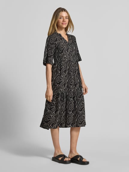 Vrouwenmodel draagt Ausgestelltes Maxikleid aus reiner Viskose Modell 'EASY JOY' van Vero Moda, zwart met wit all-over patroon, uitlopend, maxi, Henley-hals, korte knoopsluiting, 1/2-mouw, rechte zoom, pure viscose, voorkant volledige lichaamsopname.
