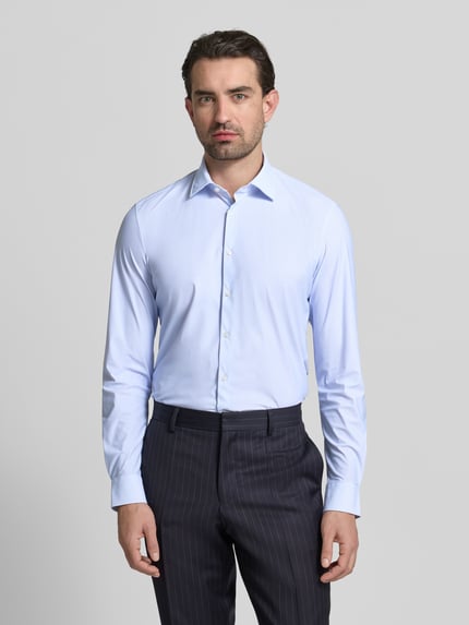 Mannenmodel draagt Slim Fit Business-Hemd met Kentkraag van Jake*s in lichtblauw, elastische materiaalmix, knoopsluiting, met lange mouwen, effen textuur, zakelijk ontwerp, voorkant geheel zichtbaar, Ganzkörperansicht von vorne.