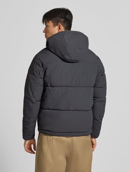 Männermodel trägt Steppjacke mit Kapuze Modell 'GALAXY' von JACK & JONES in Dunkelgrau, glatte Oberfläche, Ganzkörperansicht Rückansicht.
