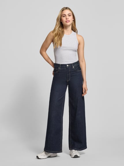 Vrouwenmodel draagt Tanktop in Ripp-Optik met Rundhalsausschnitt van Scotch & Soda in lichtgrijs, slim fit, katoenen elasthaansmix, ribstructuur, hele lichaamsopname van voren.