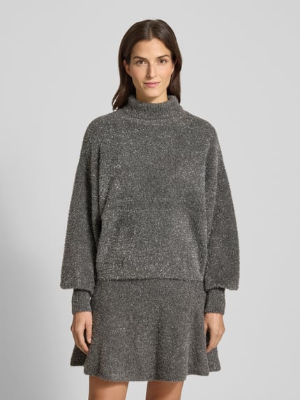 Frauenmodel trägt Strickpullover aus Effektgarn mit Rollkragen Modell 'LISTRA' von YAS, schimmernd, Material-Mix mit Viskose-Mix, Relaxed-Fit; dunkelgraue, strukturierte Oberfläche, Rücklänge 59 cm, Ärmellänge 57 cm, Ganzkörperansicht von vorne.
